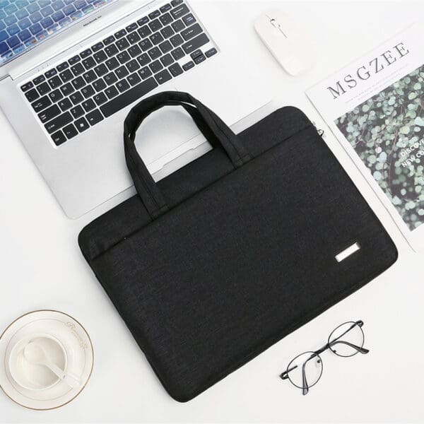 Stylish black laptop bag on a sleek workspace with modern tech and personal touches.