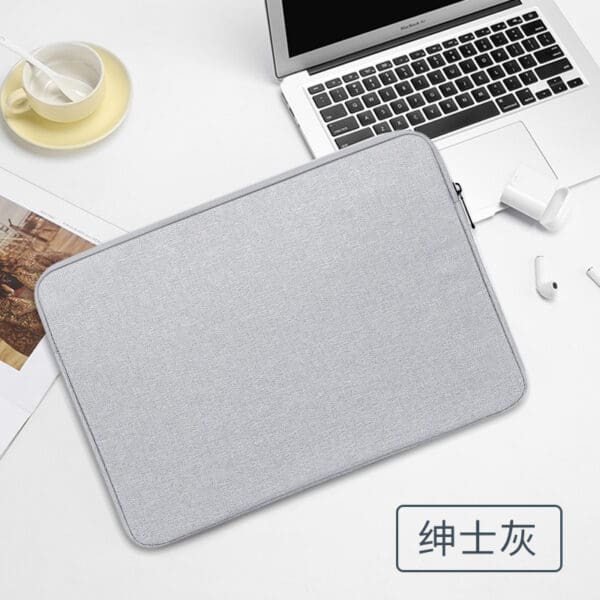 Sleek gray laptop sleeve with coffee and earbuds, perfect for modern workspaces.