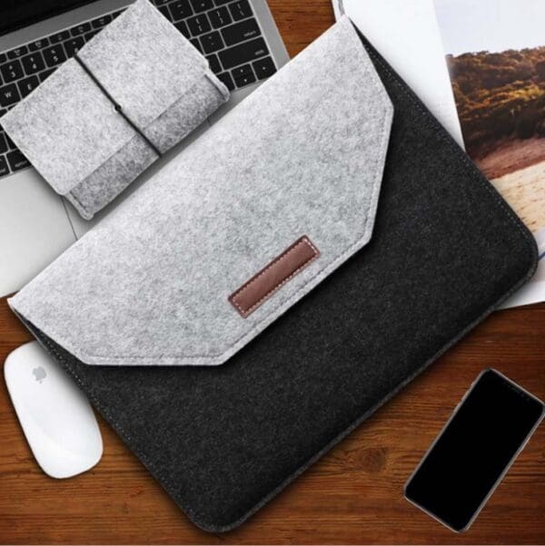 Modern felt laptop sleeve with accessories on a wooden surface, perfect for organized workspaces.