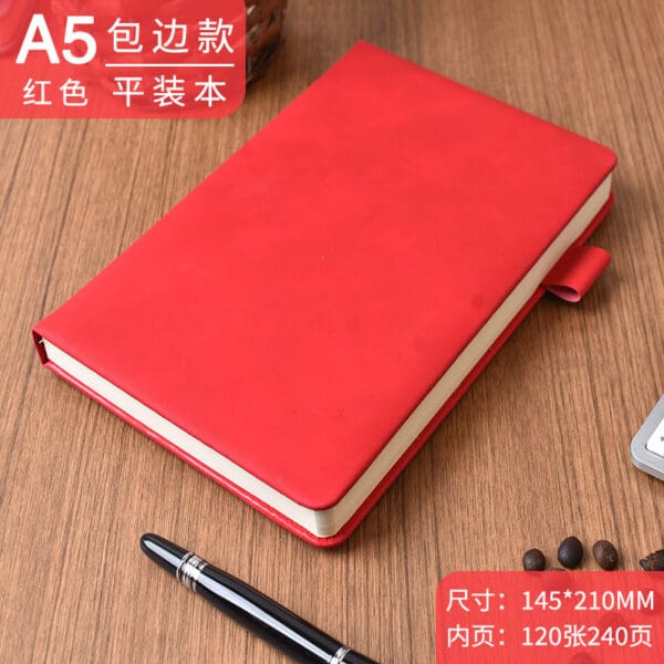 Red A5 notebook with black pen and coffee beans on wooden surface, perfect for creativity.