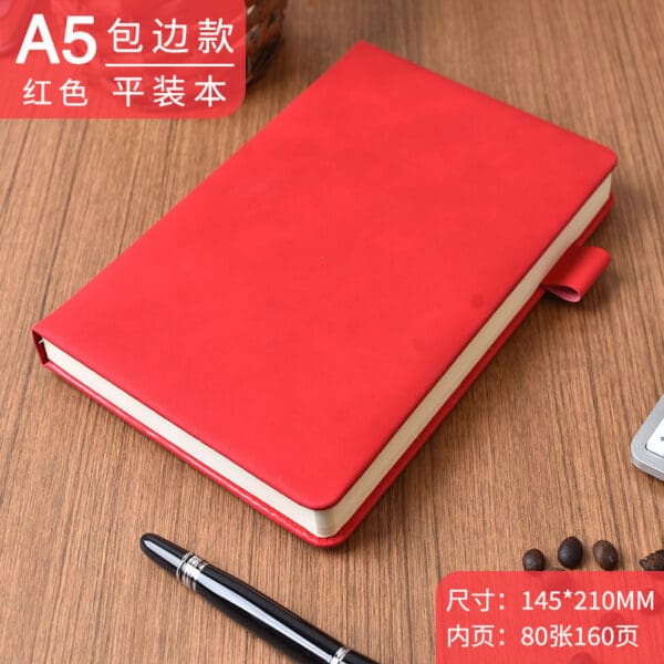Elegant red A5 notebook with pen and coffee beans on wooden surface, perfect for journaling.