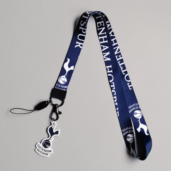 Navy blue Tottenham Hotspur lanyard with white text and cockerel emblem charm, ideal for fans.